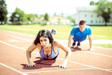 Fototapeta premium Young couple doing push ups on track.