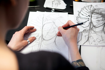 Girl tattoo artist draws a sketch. Close-up of hands © shishkin137