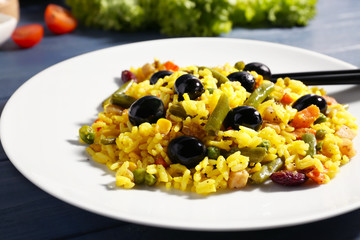 Tasty rice with vegetables and olives on plate