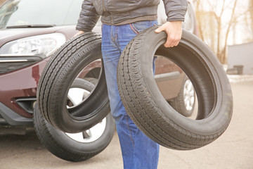 Obraz premium Man carrying two tires outdoors