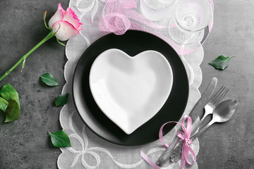 Table setting with plate in shape of heart and rose on napkin