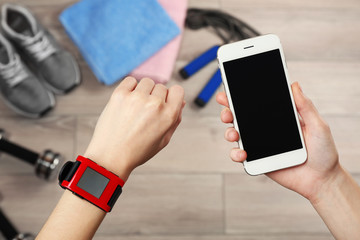 Female hands with heart rate monitor watch and smartphone, closeup