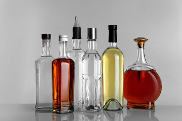 Table with different bottles of wine and spirits on gray background