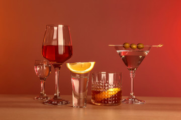 Table with glasses of wine and spirits on color background