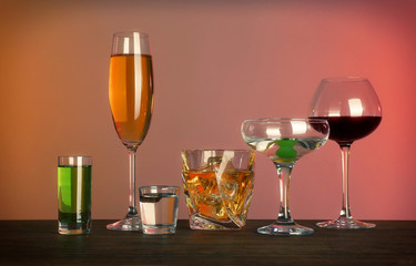 Table with glasses of wine and spirits on color background