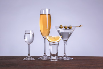 Table with glasses of wine and spirits on color background