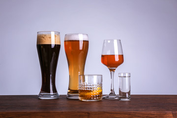 Table with glasses of wine and spirits on color background