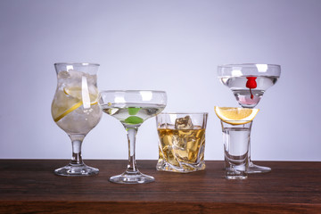 Table with glasses of wine and spirits on color background