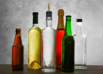 Different bottles of wine and spirits on color background