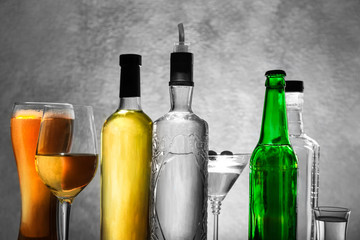 Different bottles of wine and spirits on color background