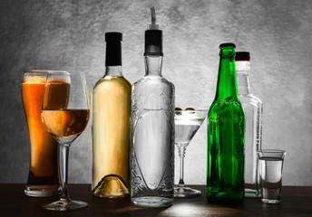 Different bottles of wine and spirits on color background