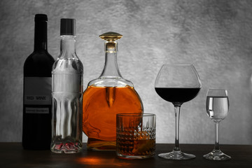Different bottles of wine and spirits on color background