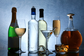 Different bottles of wine and spirits on color background