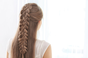 Young beautiful woman with nice braid hairstyle on light background - obrazy, fototapety, plakaty