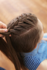 Hairdresser making braid hairstyle to young beautiful woman, closeup