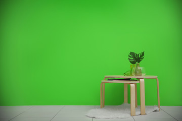 Tables with home decor on greenery wall background