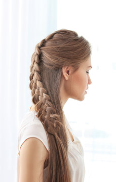 Young beautiful woman with nice braid hairstyle on light background