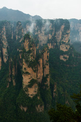 mountains are surrounded by clouds at Zhangjiajie, a national park in China known for its surreal scenery of rock formations.