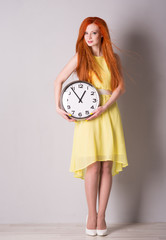 woman with red hair holding a big clock