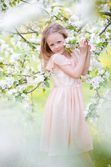 Little adorable girl in blooming cherry tree garden outdoors on Easter eve