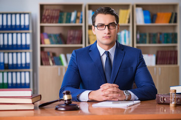 Handsome judge with gavel sitting in courtroom