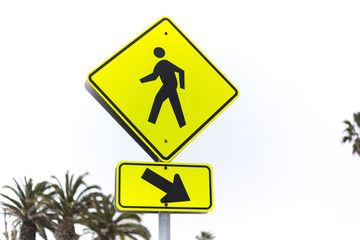 Yellow road sign pedestrian crossing and palm tree