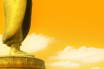 abstract foot of gold buddha and buddhism sacred on clear warm or orange sky with white cloud at Thipsukhontharam temple for background and copy space