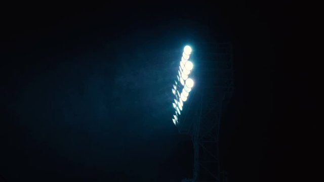 Searchlight tower on a dark sky background. Mast with spotlights illuminate on stadium and night sky background. Multiple sport light. A mast with a searchlight in a sports stadium.