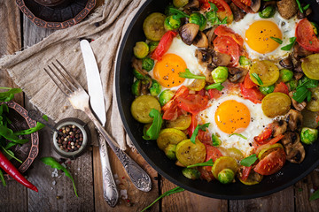 Fototapeta na wymiar Breakfast for two. Fried eggs with vegetables - shakshuka in a frying pan on a wooden background in rustic style. Flat lay. Top view