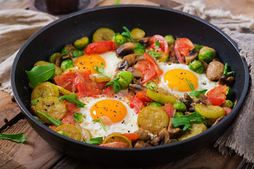 Breakfast for two. Fried eggs with vegetables - shakshuka in a frying pan on a wooden background in rustic style.