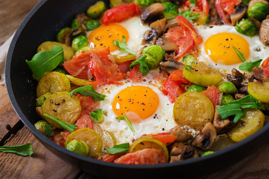 Breakfast for two. Fried eggs with vegetables - shakshuka in a frying pan on a wooden background in rustic style.