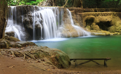 waterfall with relax long wood chair and clear blue and green water with tree and root in the jungle at Huay Mae Khamin waterfall for nature landscape