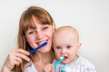 Mother and her baby brushing teeth together