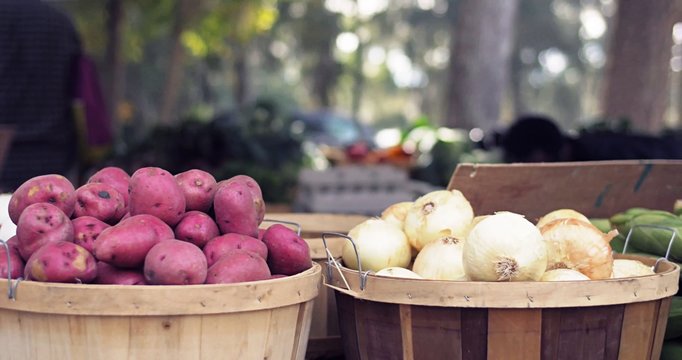 Red potatoes and white onions on a wooden bucket in the market. Fresh vegetables open air market background.