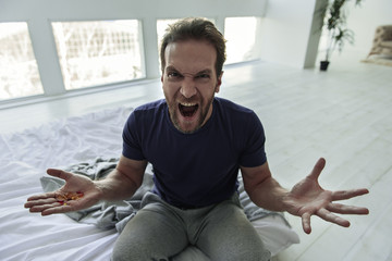 Angry male person sitting on bed