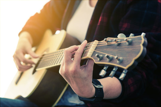 woman's hands playing acoustic guitar, close up