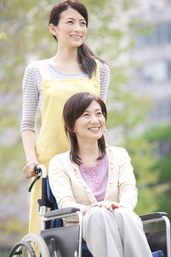 Caretaker pushing mature woman on wheelchair