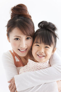 Portrait of woman embracing daughter, smiling, white background