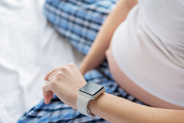 Obraz na płótnie Canvas Pregnant woman checking time on watch