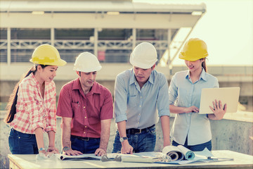 Multi-ethnic group of engineers meeting at terrace on top of construction site with evening light