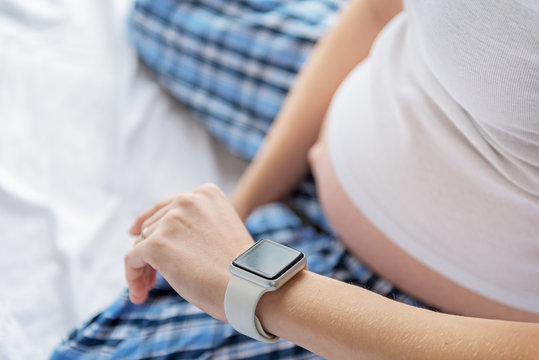 Pregnant woman checking time on watch
