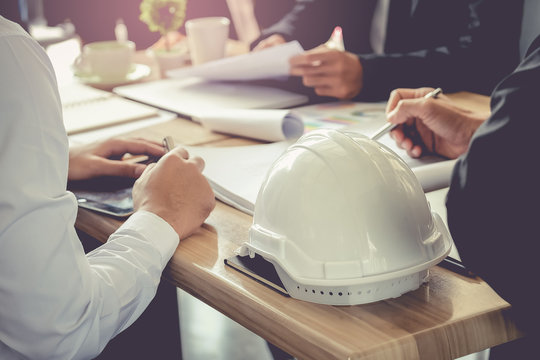 Architect And Businessman Planning Meeting To Work With Commitment, Set Mind.Focus White Safety Helmets Is Foreground.