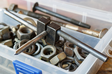 Machine tap with the old bolts and nuts in a storage box