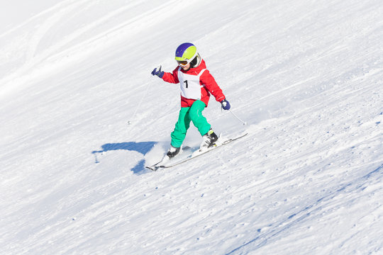 Little skier racing in snowy mountain slope
