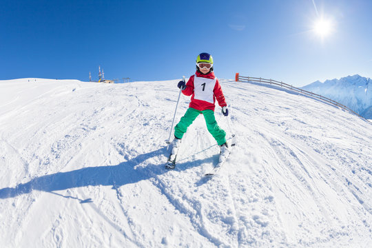 Little skier riding down a hill in alpine resort