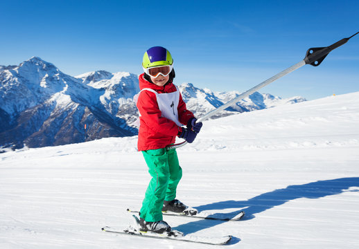 Cute skier at surface lift against mountain scene