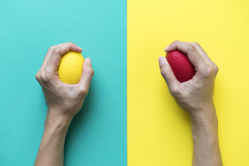 Hands of a woman holding a stress ball on colorful background