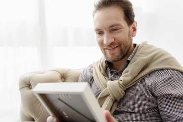 Joyful guy observing interesting photograph