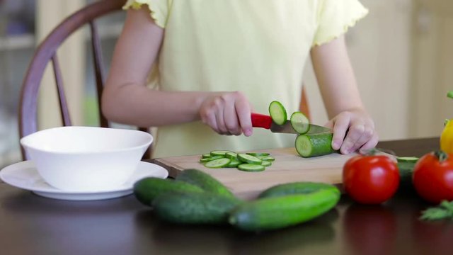 Little girl cutting vegetable for salad.
