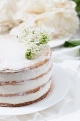 Obraz na płótnie Canvas Rustic wedding cake with white lilac on a white table, close up, selective focus